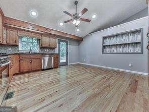 kitchen featuring backsplash, light hardwood / wood-style flooring, ceiling fan, and appliances with stainless steel finishes