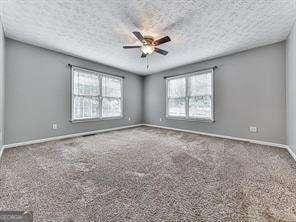 spare room featuring ceiling fan, a wealth of natural light, and a textured ceiling