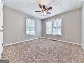 carpeted empty room featuring ceiling fan and a textured ceiling