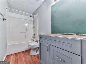 full bathroom with vanity, tub / shower combination, hardwood / wood-style floors, and toilet