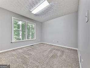 unfurnished room featuring lofted ceiling, carpet flooring, and a textured ceiling