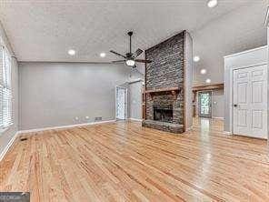 unfurnished living room featuring hardwood / wood-style flooring, ceiling fan, and a fireplace