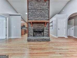 unfurnished living room with high vaulted ceiling, a fireplace, and hardwood / wood-style floors