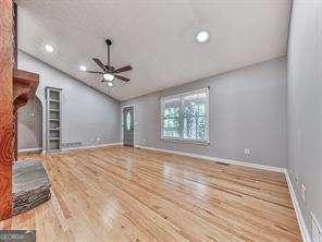 unfurnished living room with hardwood / wood-style flooring, ceiling fan, and lofted ceiling