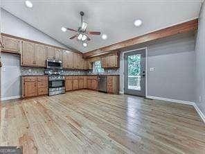 kitchen with ceiling fan, stainless steel appliances, vaulted ceiling, and wood-type flooring