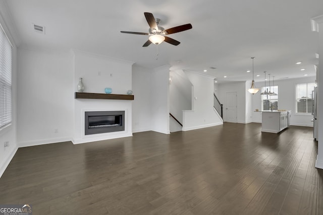 unfurnished living room featuring dark wood-type flooring, ceiling fan, and ornamental molding