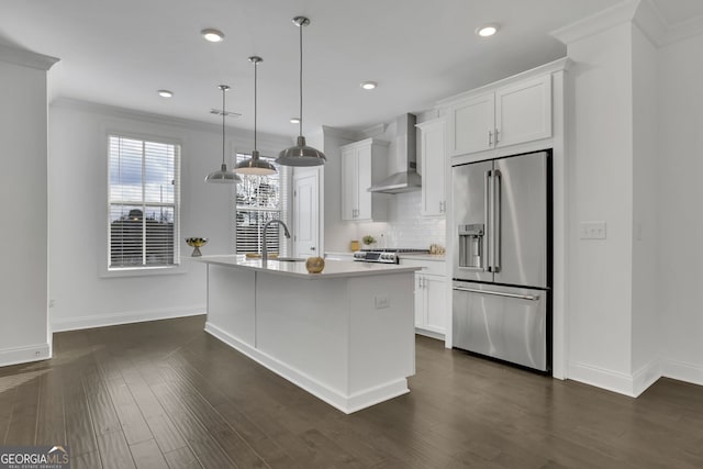 kitchen with white cabinetry, high quality fridge, an island with sink, and wall chimney exhaust hood