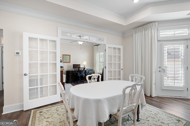 dining space with dark wood-type flooring, ornamental molding, french doors, and a raised ceiling