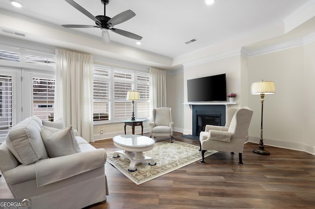 living room featuring crown molding, ceiling fan, dark hardwood / wood-style flooring, and a tray ceiling