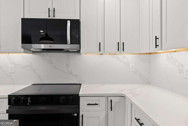 kitchen with white cabinetry, black range with electric stovetop, and light stone counters