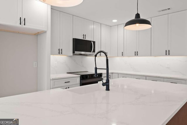 kitchen with hanging light fixtures, white cabinetry, backsplash, and light stone counters