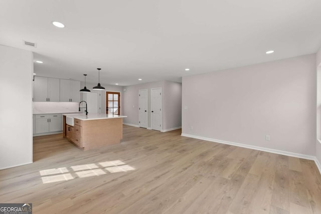 kitchen featuring white cabinetry, a spacious island, decorative light fixtures, and light hardwood / wood-style floors