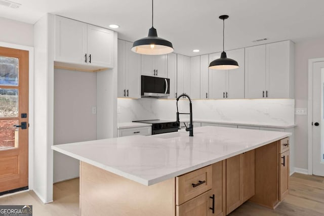 kitchen with white cabinetry, light stone countertops, a kitchen island with sink, and hanging light fixtures