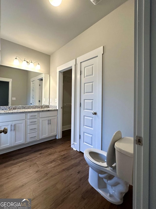 bathroom featuring vanity, wood-type flooring, and toilet