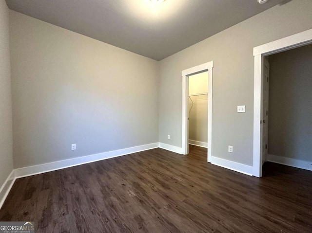 unfurnished bedroom with a walk in closet, dark hardwood / wood-style flooring, and a closet