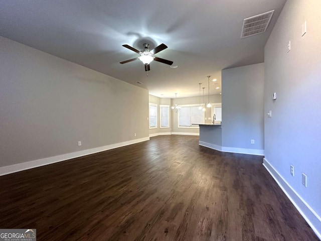 unfurnished living room featuring dark hardwood / wood-style flooring, sink, and ceiling fan with notable chandelier