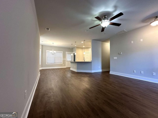 unfurnished living room featuring ceiling fan with notable chandelier and dark hardwood / wood-style floors