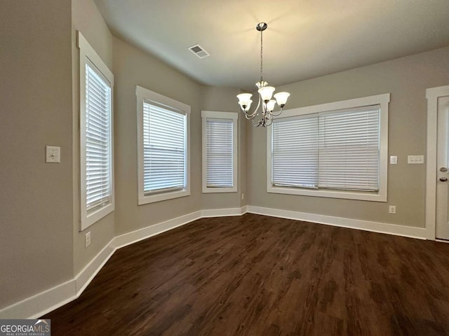 unfurnished dining area with dark hardwood / wood-style floors and a chandelier