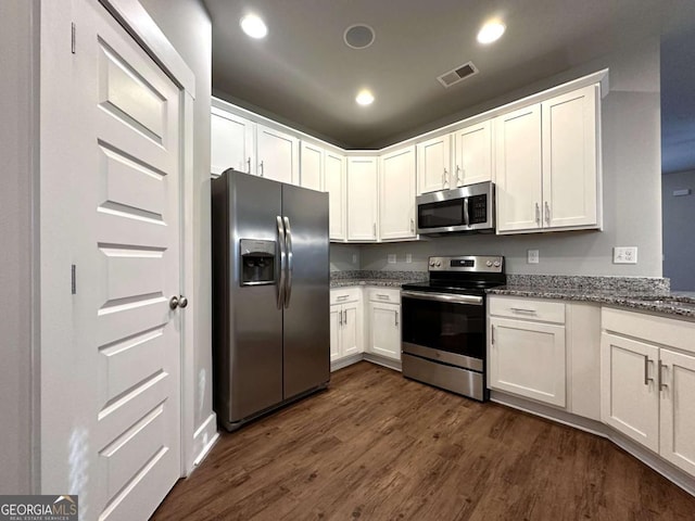 kitchen with white cabinetry, appliances with stainless steel finishes, dark hardwood / wood-style floors, and dark stone countertops