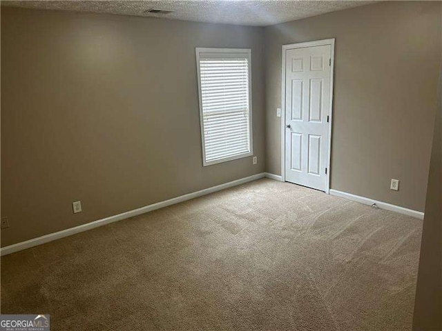 empty room featuring light carpet and a textured ceiling