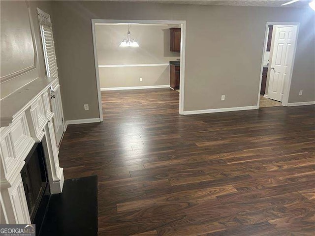 unfurnished living room with dark hardwood / wood-style floors and a chandelier