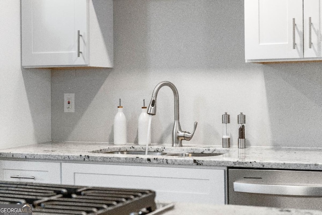 kitchen featuring light stone countertops, sink, and white cabinets