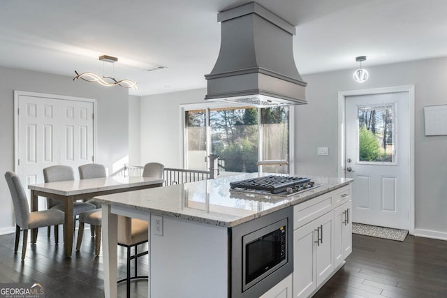 kitchen featuring premium range hood, white cabinets, hanging light fixtures, a center island, and stainless steel appliances