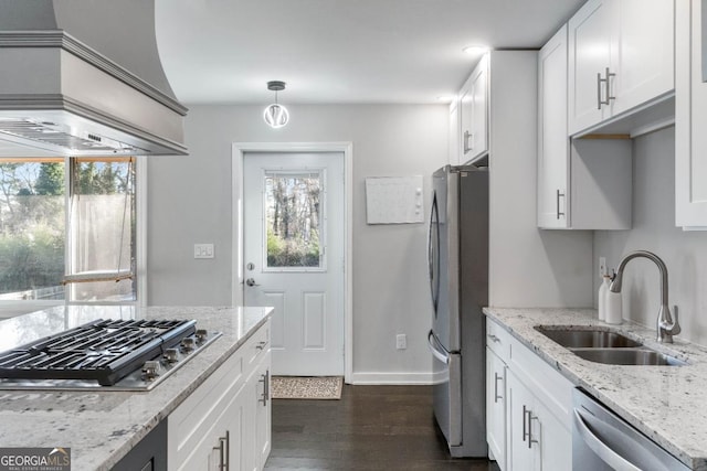 kitchen featuring premium range hood, sink, white cabinetry, light stone counters, and appliances with stainless steel finishes