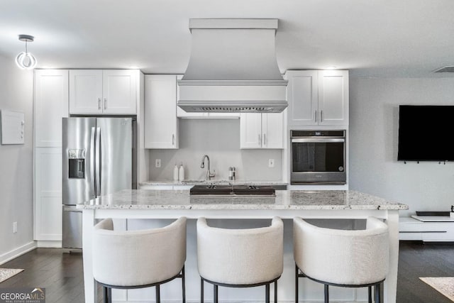 kitchen with stainless steel appliances, light stone countertops, custom exhaust hood, and white cabinets