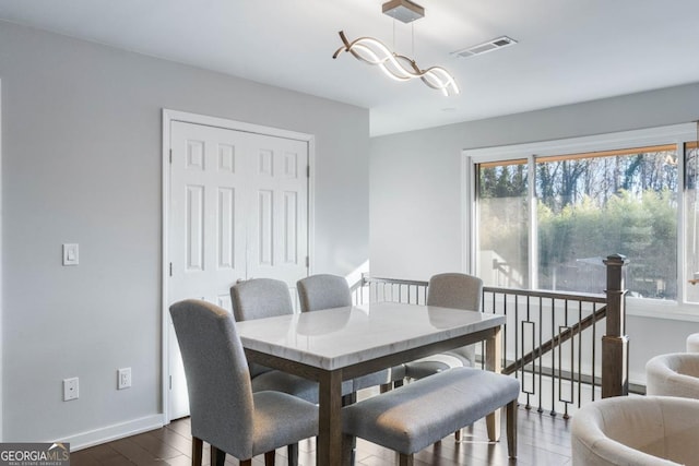 dining area with dark hardwood / wood-style flooring and an inviting chandelier