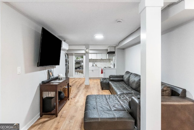 living room with decorative columns, sink, and light hardwood / wood-style flooring