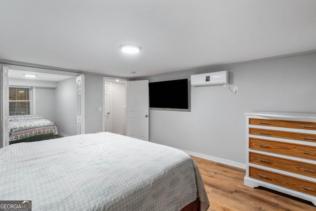 bedroom with light hardwood / wood-style floors and a wall mounted AC