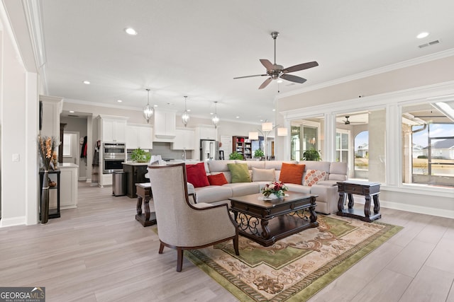 living room with ornamental molding, light hardwood / wood-style floors, and ceiling fan