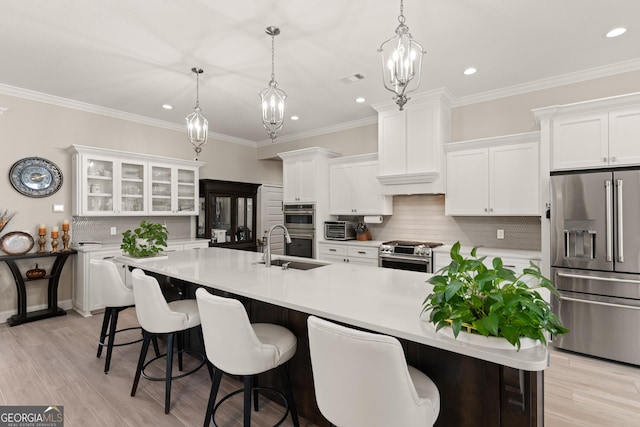 kitchen featuring high end appliances, white cabinetry, an island with sink, and a breakfast bar