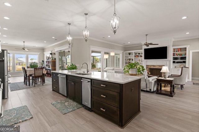 kitchen with sink, hanging light fixtures, dark brown cabinets, stainless steel appliances, and a center island with sink