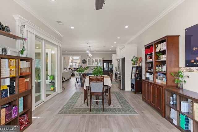 dining space featuring an inviting chandelier, crown molding, and light hardwood / wood-style floors