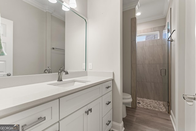 bathroom with hardwood / wood-style flooring, vanity, toilet, a shower with door, and crown molding