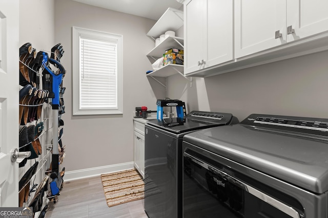 laundry room featuring cabinets, washer and dryer, and light hardwood / wood-style flooring