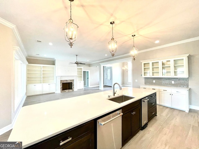 kitchen with stainless steel dishwasher, decorative light fixtures, sink, and white cabinets