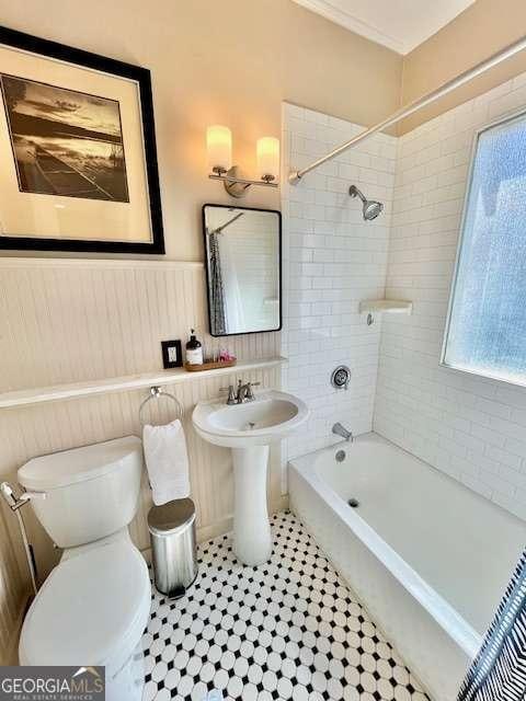 bathroom with tiled shower / bath, a healthy amount of sunlight, and toilet