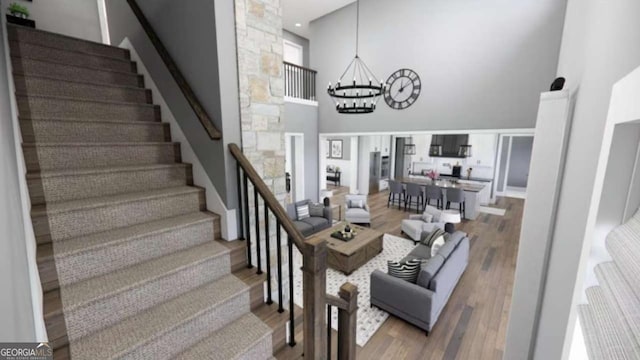 living room with a towering ceiling, a chandelier, and hardwood / wood-style floors