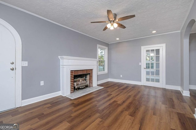 unfurnished living room with dark hardwood / wood-style flooring, crown molding, a fireplace, and a textured ceiling