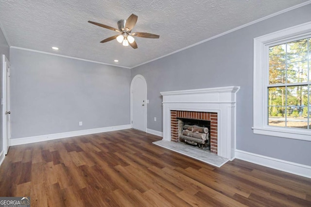 unfurnished living room featuring a brick fireplace, ornamental molding, dark hardwood / wood-style floors, and ceiling fan