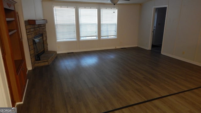 unfurnished living room featuring ceiling fan, a stone fireplace, and dark hardwood / wood-style flooring