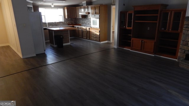 kitchen featuring sink, a center island, dark hardwood / wood-style floors, white appliances, and backsplash