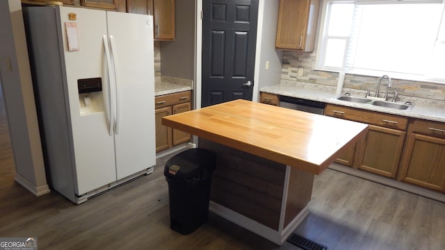 kitchen with sink, white refrigerator with ice dispenser, a kitchen island, dark hardwood / wood-style flooring, and decorative backsplash