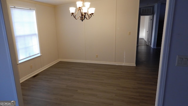 empty room featuring dark wood-type flooring and a notable chandelier