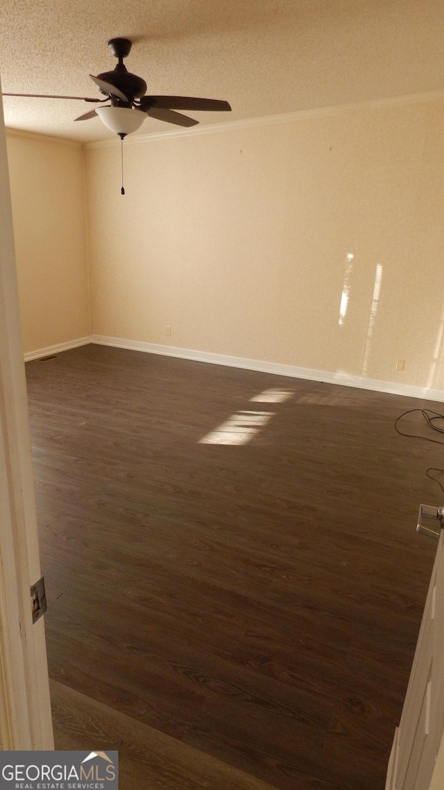 empty room featuring ceiling fan, dark hardwood / wood-style floors, and a textured ceiling