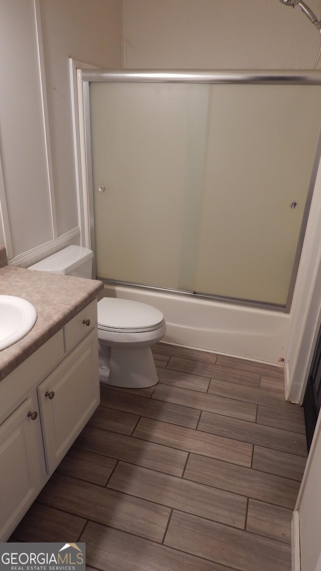 full bathroom featuring toilet, vanity, and bath / shower combo with glass door