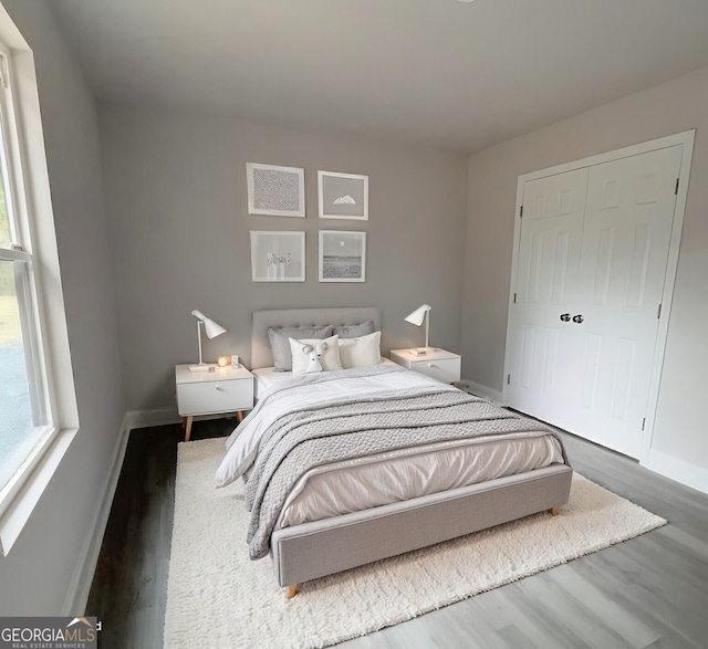 bedroom with multiple windows, baseboards, and wood finished floors